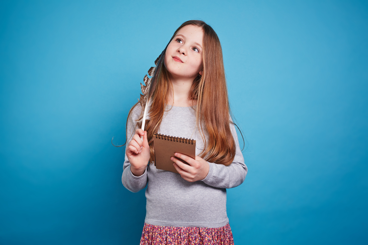Young girl holding a notebook and thinking about what she is going to write about