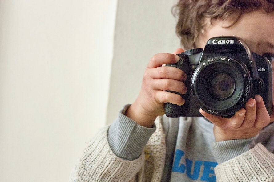 kid holding a cannon camera up to his face