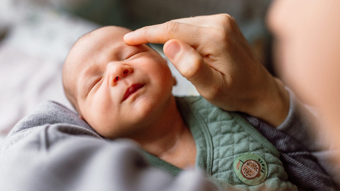 tiny new baby being held with eyes closed