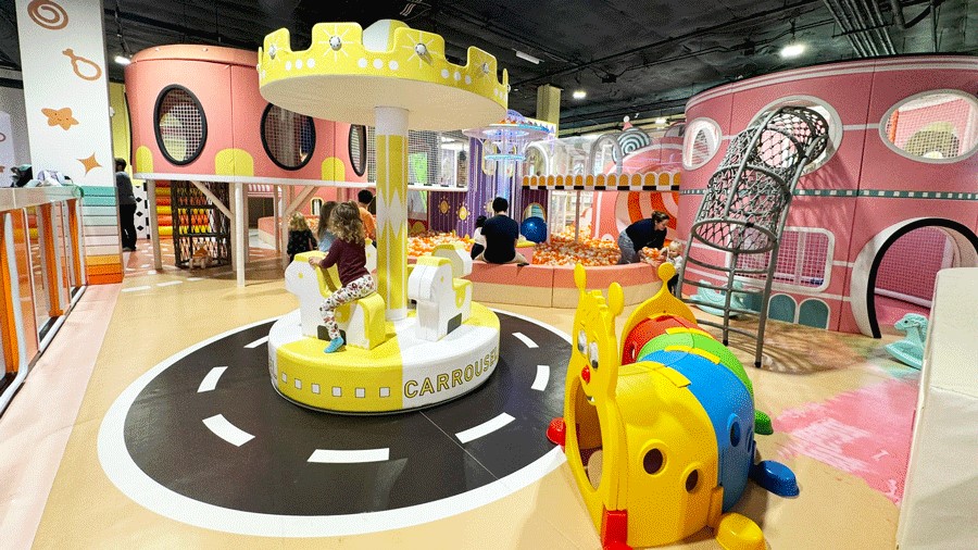Young girl at an indoor playground in Bellevue, Twinkle Land Play Cafe, that has a carousel and other play structures.