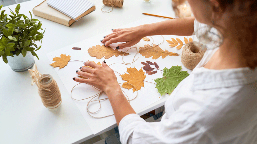 a woman strings leaves together for a fall craft for adults to make at a DIY party