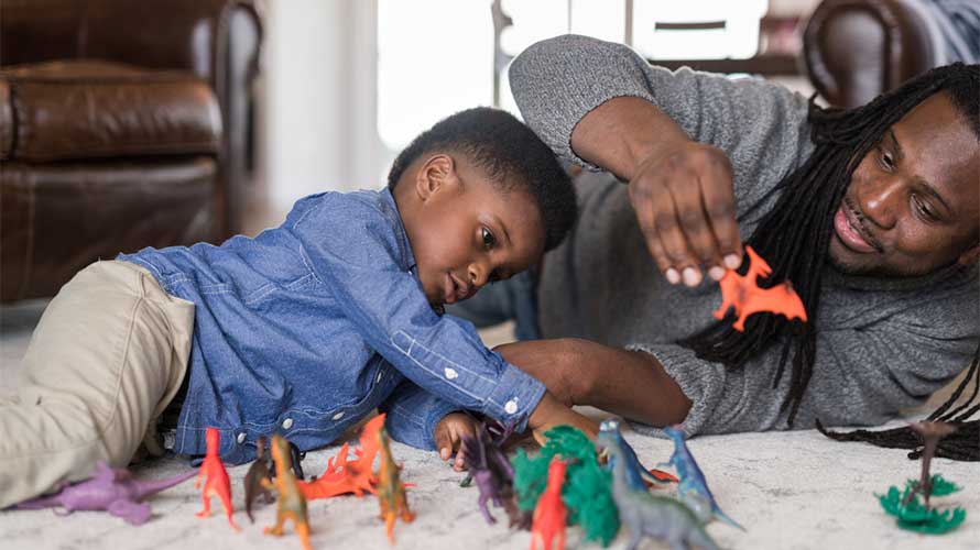 father and son playing with dinosaur figurines