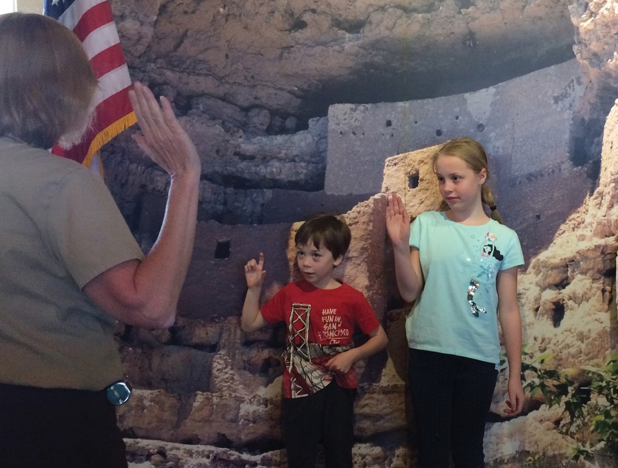 Two children raising their right hands and becoming Junior Rangers