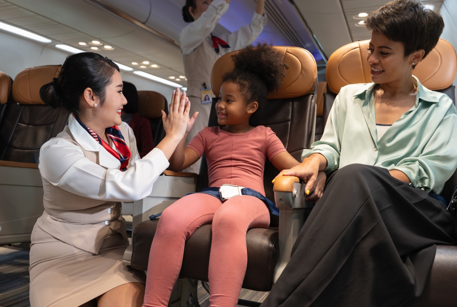 mom and daughter on an airplane, daughter is giving a flight attendant a high five