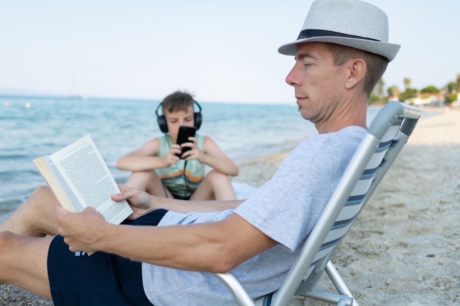 dad sitting on the beach reading a book