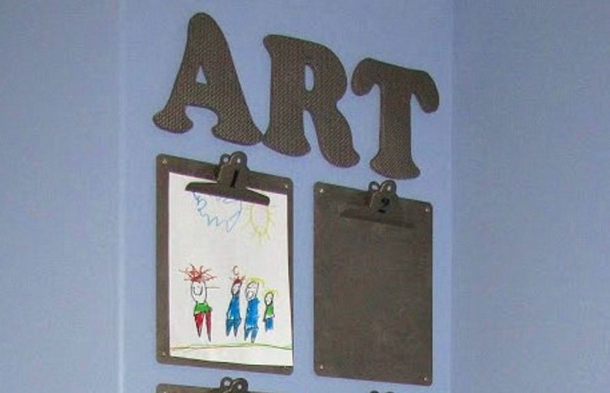 Clipboards hanging on a wall displaying kid art