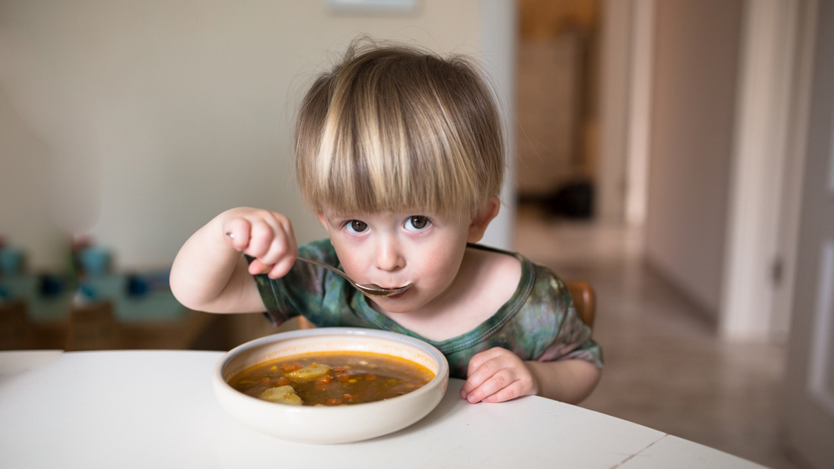 young boy eating a bowl of warm soup