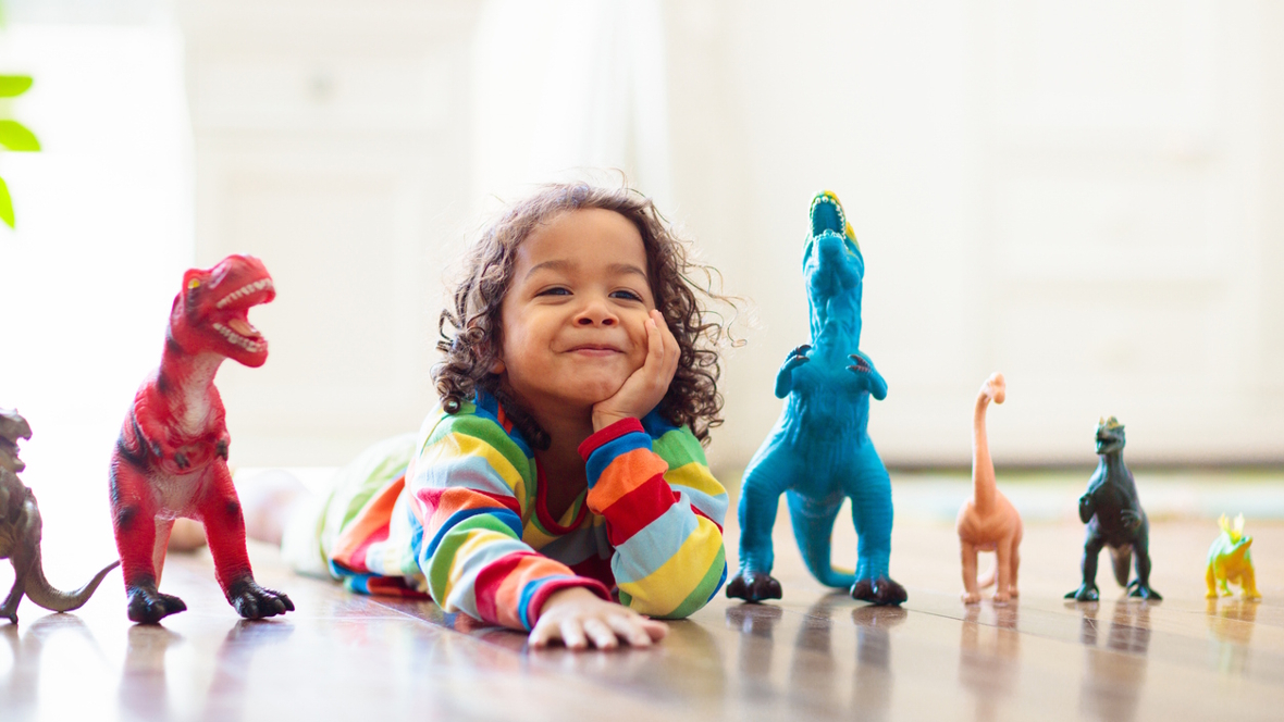 boy on the floor with toy dinosaurs
