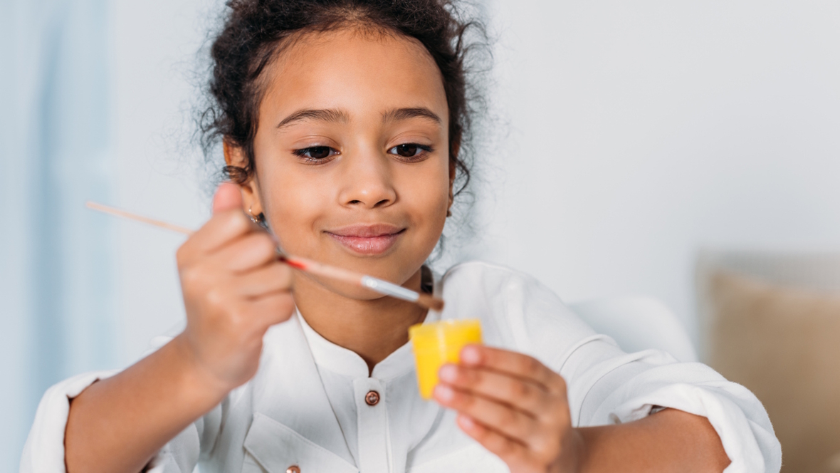 Girl painting a small jar yellow