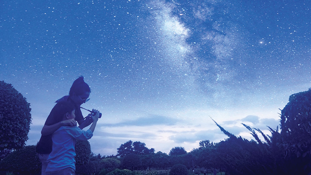 parent and child outside at night looking at stars
