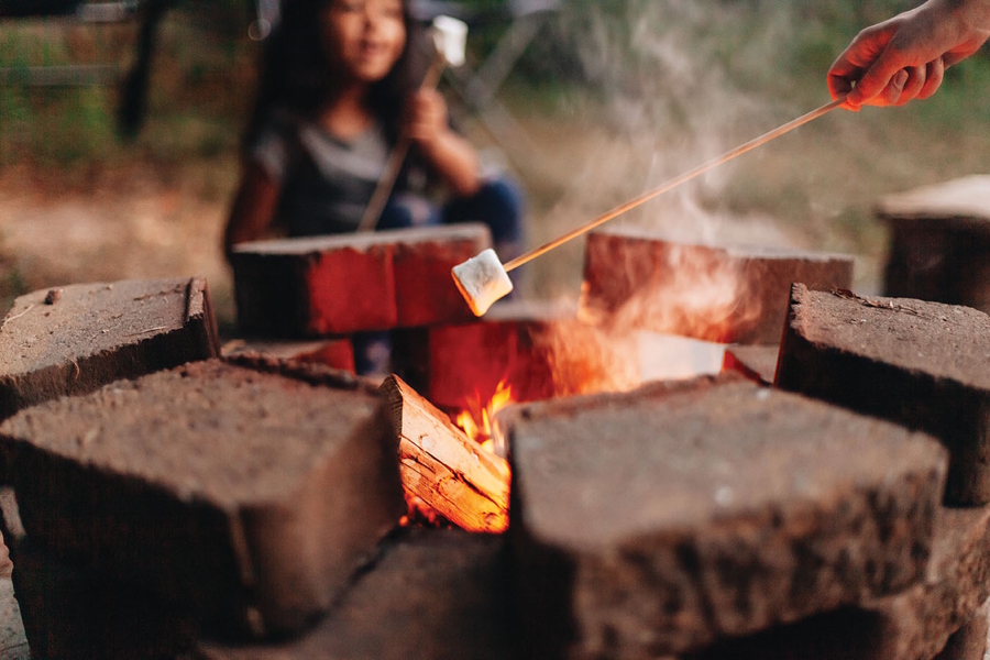 roasting marshmallows over a fire outside at night in the summer