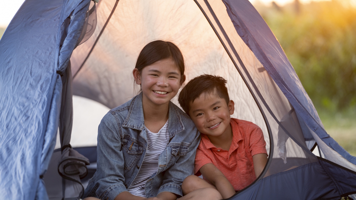 kids smiling in a tent camping in the backyard