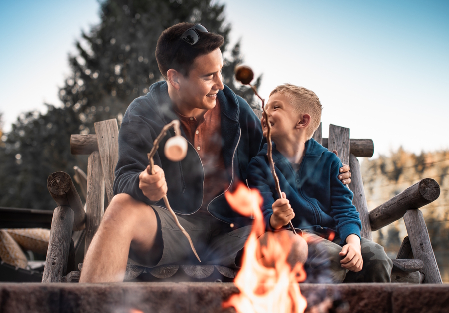 dad and son roasting marshmallows in the backyard