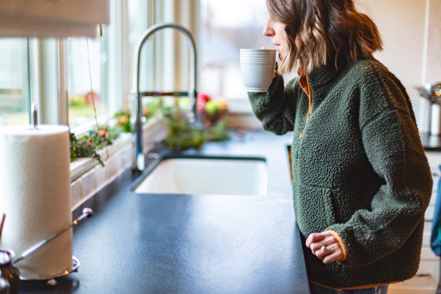 woman drinking coffee in the kitchen looking out the window