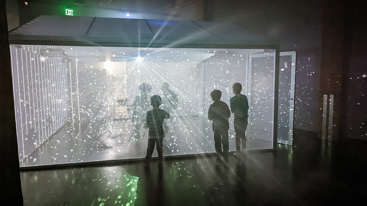Kids play in a Scottish garden shed art installation during a rainstorm at newly opened WNDR Seattle Museum