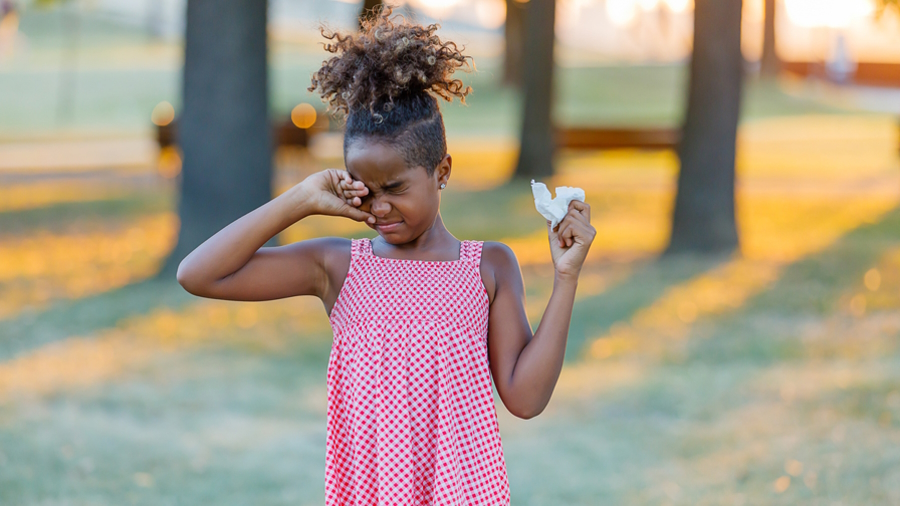 Little girl outside rubbing her eyes because she has spring allergies