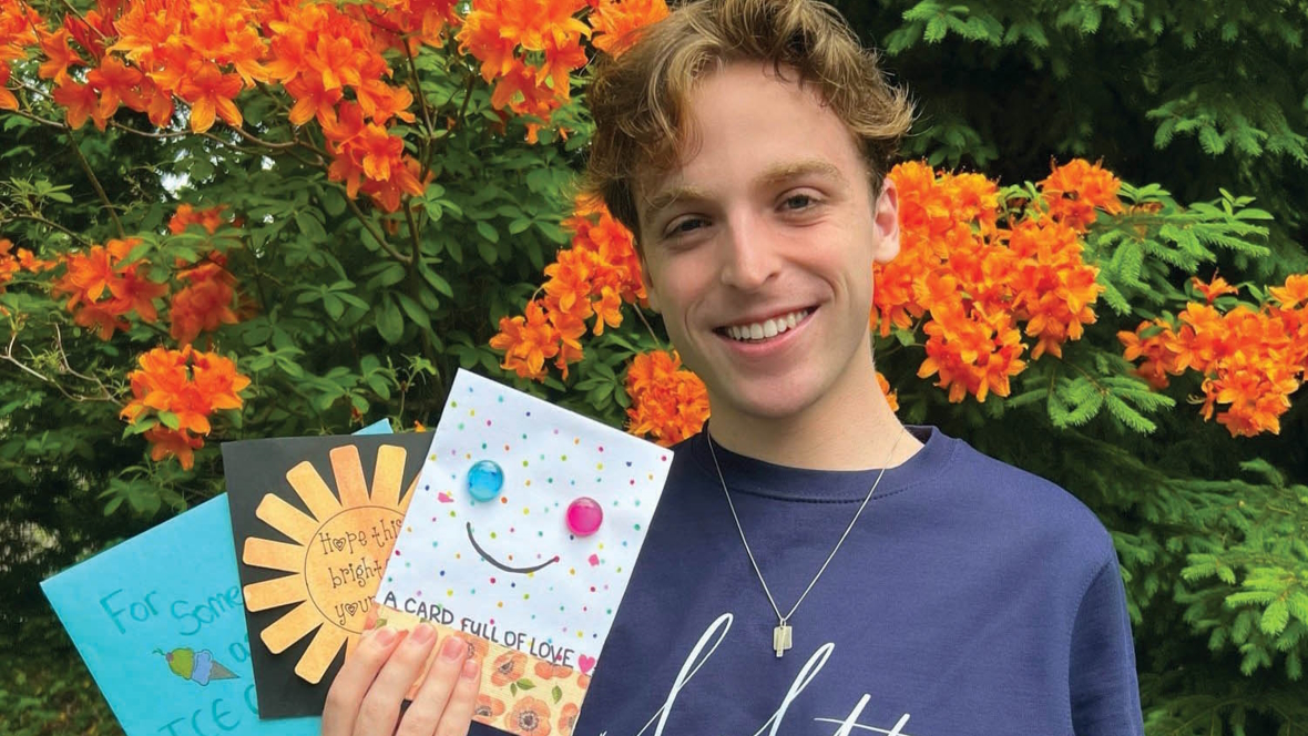 Boy holding up several hand made cards