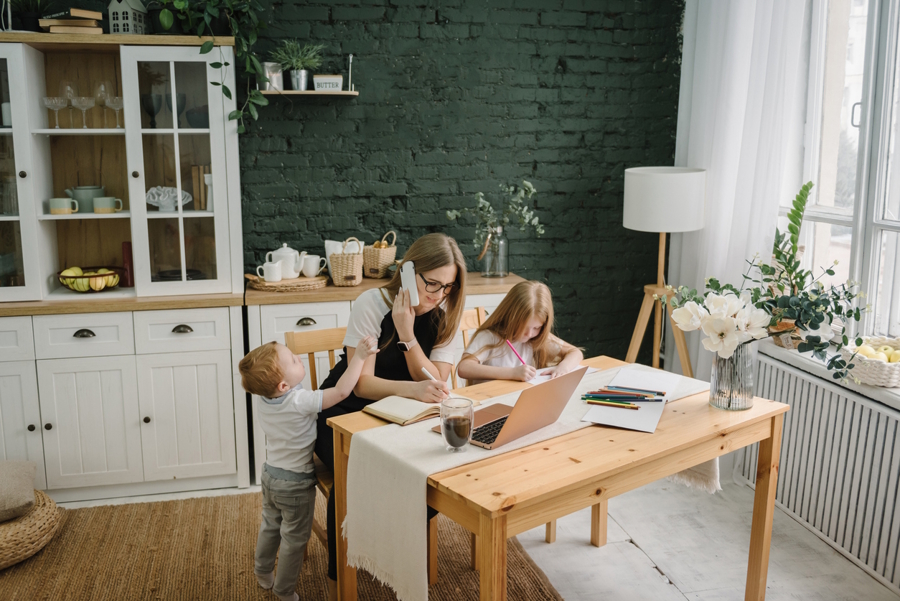 mom working at home with two kids on the phone and working on her computer