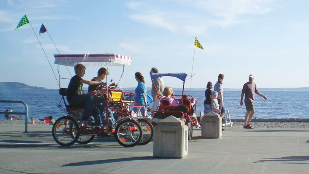 A family riding a covered bike on Alki beach