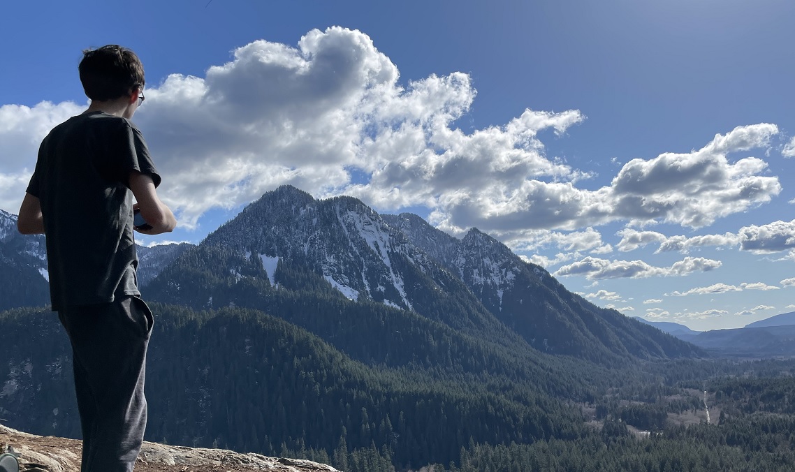 A youth hiker takes a water break and enjoys the view from the Garfield Ledges trail accessible from newly updated Middle Fork Snoqualmie Road near Seattle