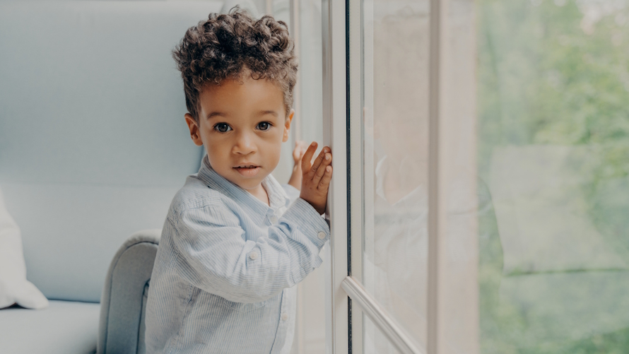 Young boy standing by a window