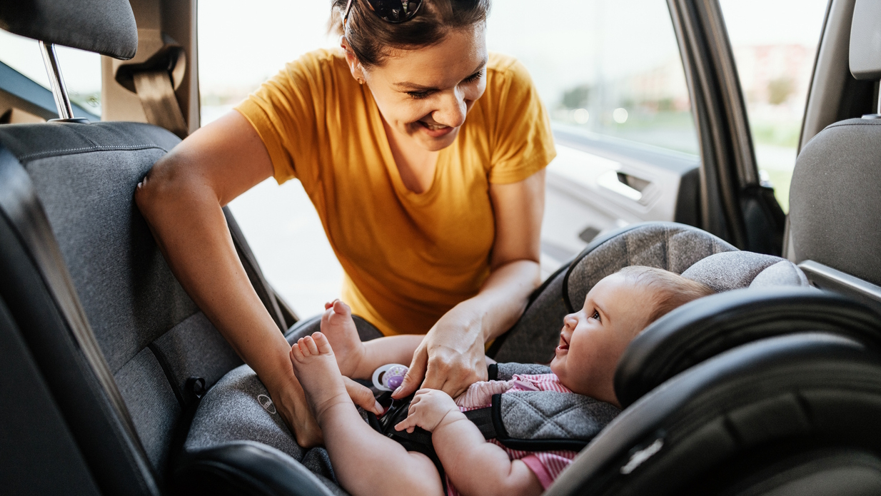 Mom putting a baby in a car seat