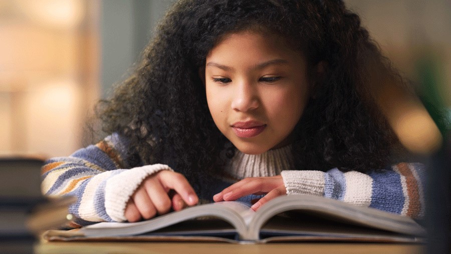 A young girl reads a book about science for kids