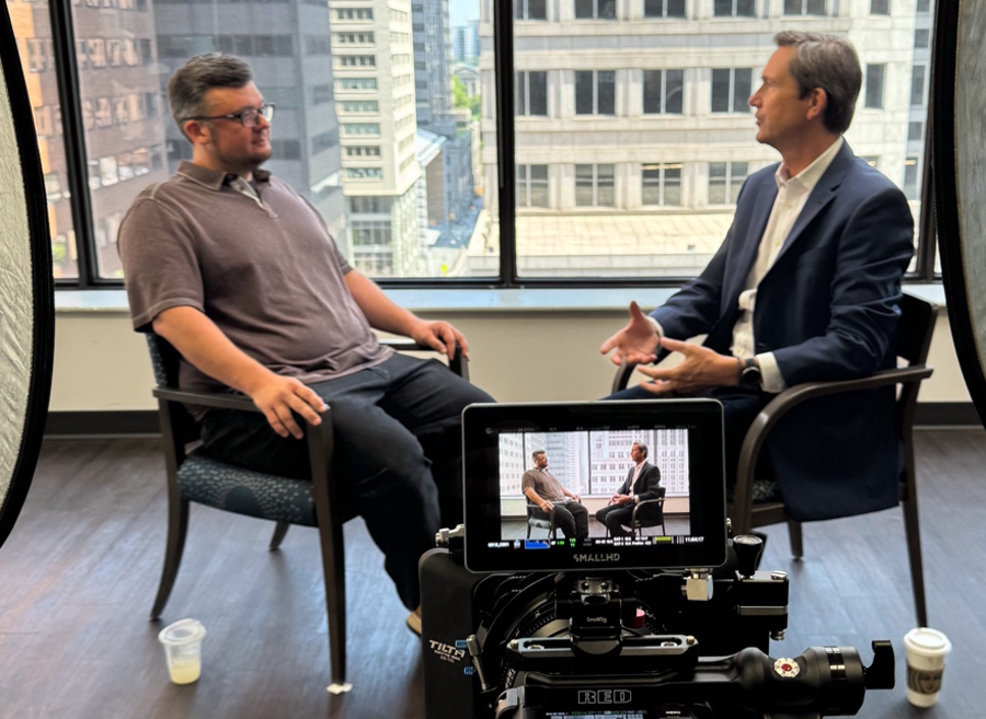 Host talking with Richard Reeves in an office building
