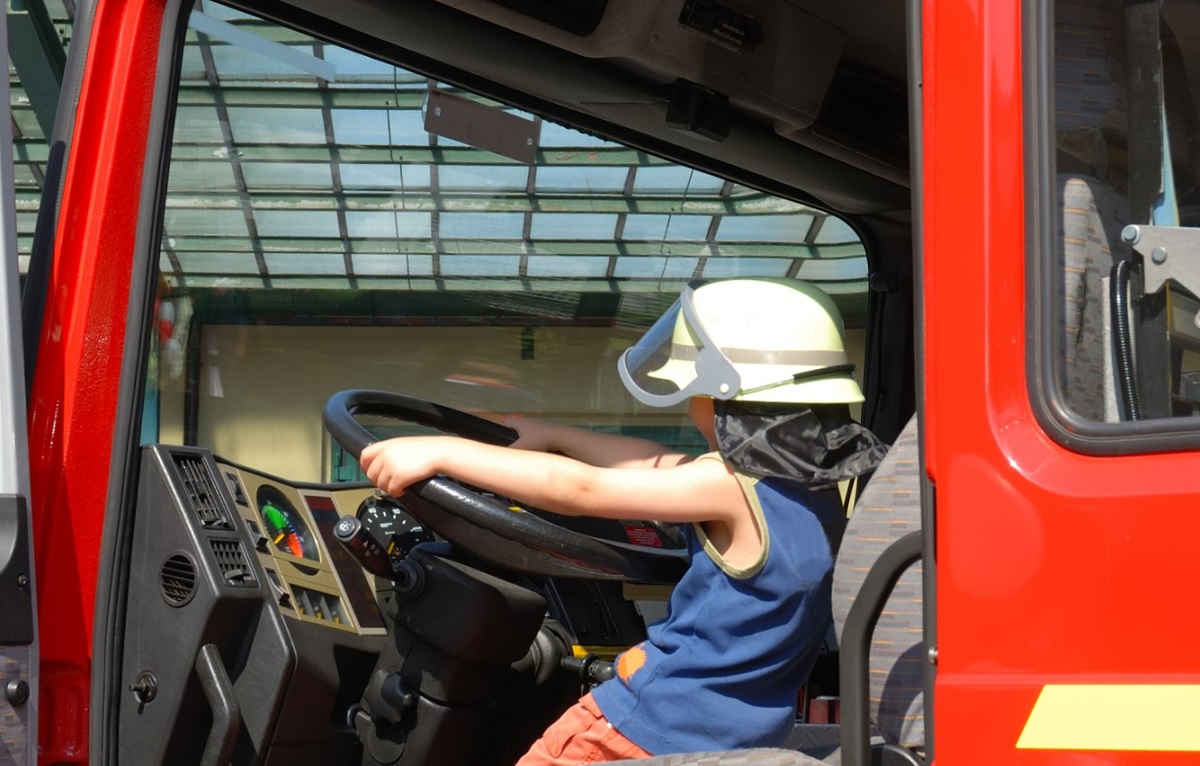 A child sits behind the wheel of a fire truck at a Seattle touch-a-truck event among family activities in Seattle for kids who love cars
