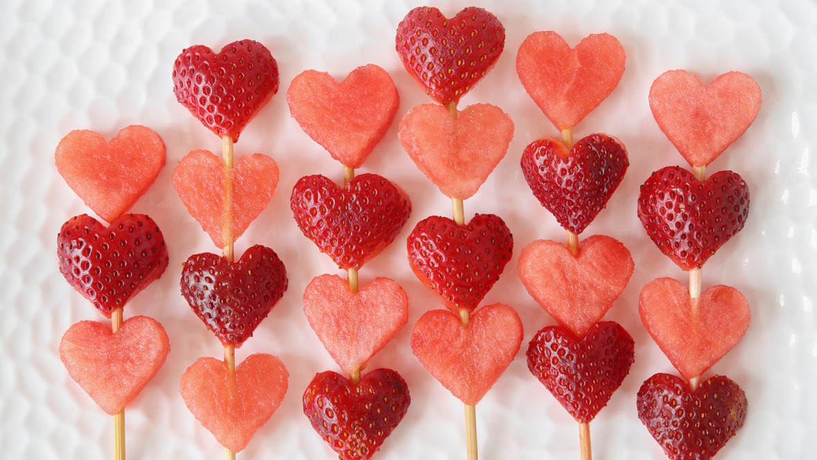 Strawberries and watermelon cut into heart shapes and put on sticks