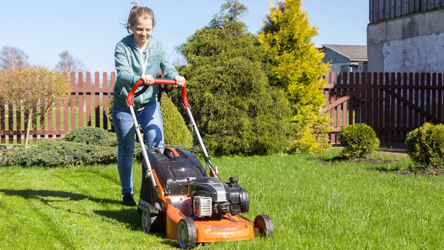 Teen girl mowing a lawn in a backyard