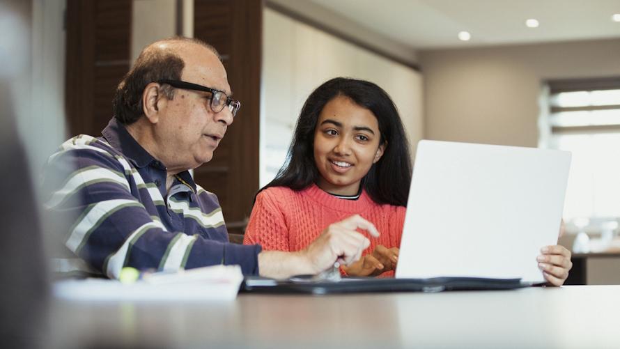 Teenager helping an older person use a computer