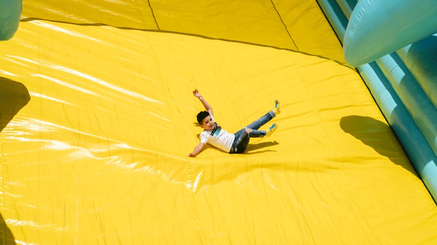 Young boy sliding down giant yellow slide at Bounce The City
