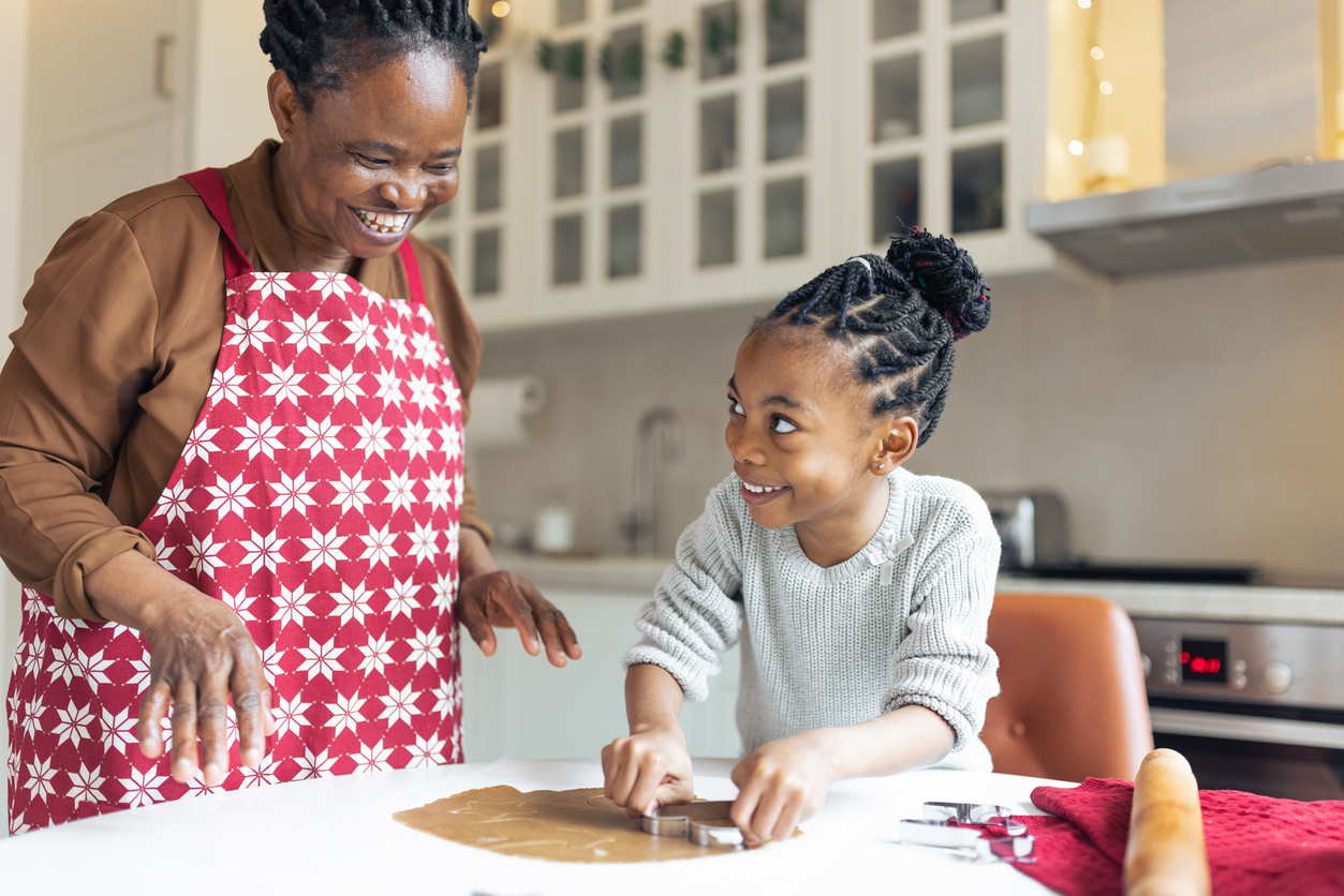 Grandmother making Christmas gingerbread cookies with her granddaughter