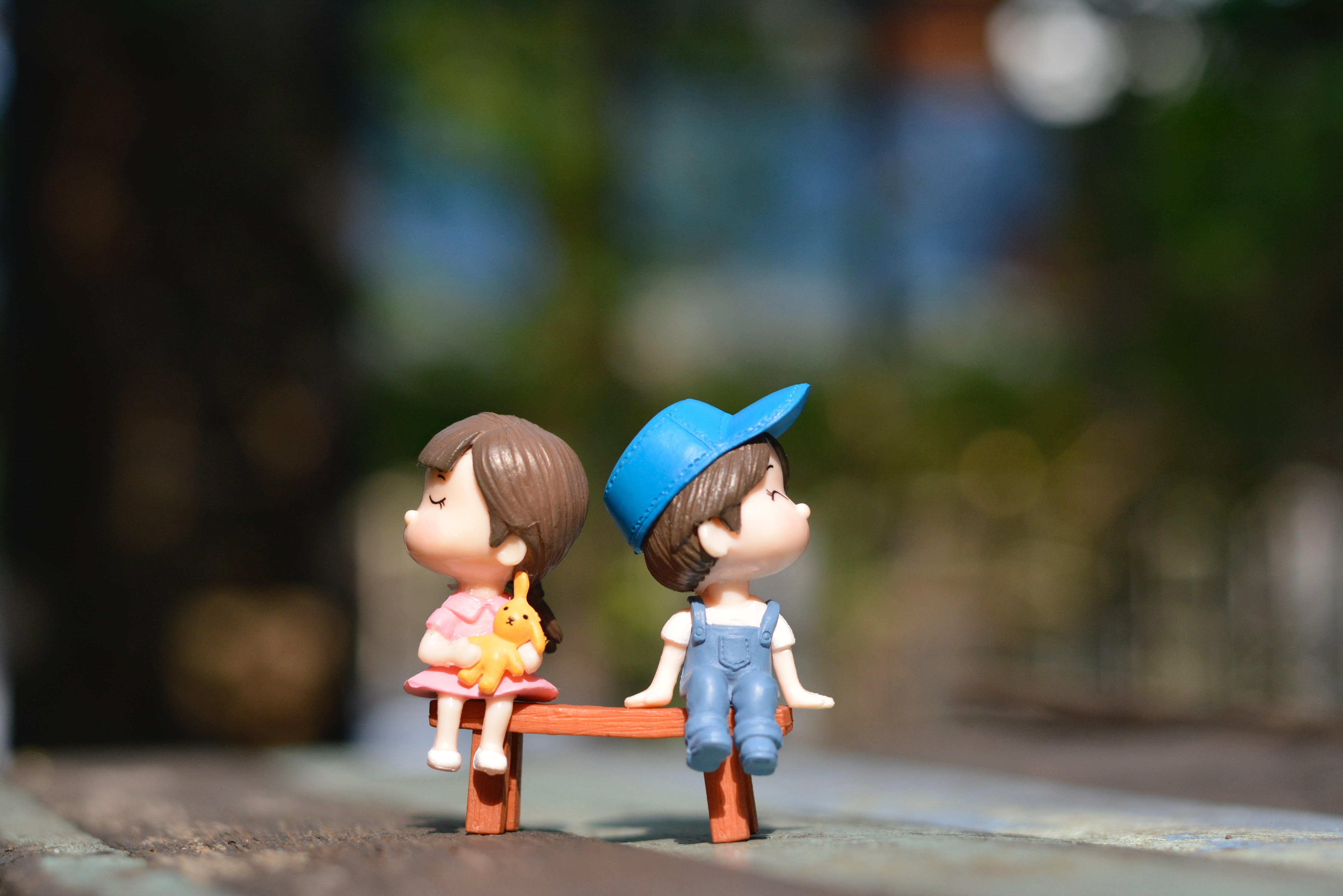 figurines awkwardly sitting on a bench