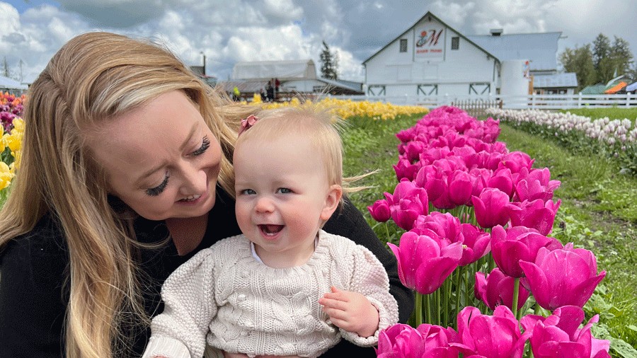 mom holding baby during Mother’s Day Baby Animal and Blooms Days surrounded by flowers