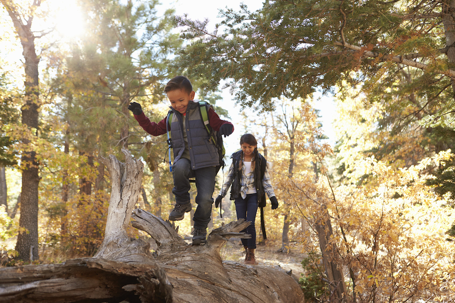 Two children hike with backpacks on while the sun is rising.