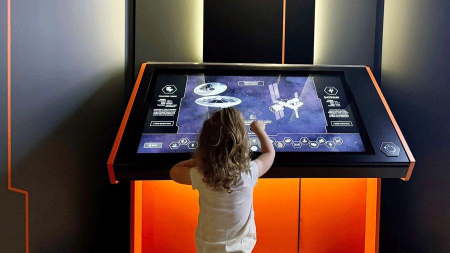 Toddler using an interactive touch screen at The Museum of Flight in Seattle for the Home Beyond Earth exhibit