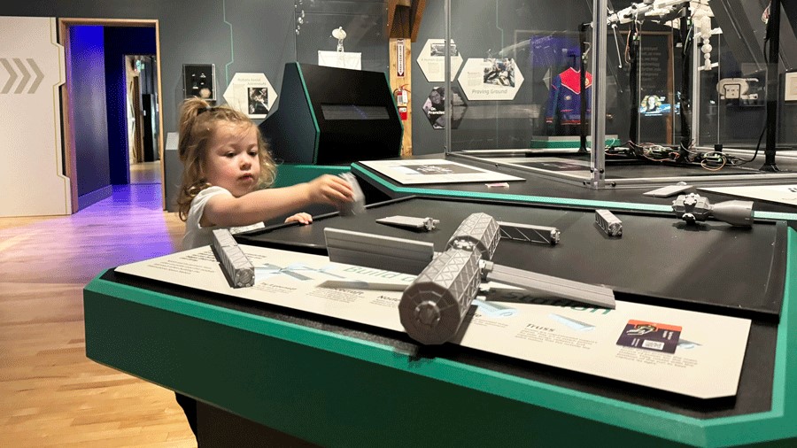Young girl builds a space station model with parts at The Museum of Flight's Home Beyond Earth exhibit