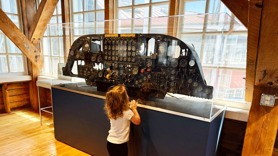 Young girl looking up at the control panel of an airplane in The Museum of Flight’s Red Barn