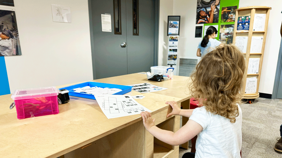 Young girl in the Aerospace Education Center at The Museum of Flight in Seattle building a paper space rover