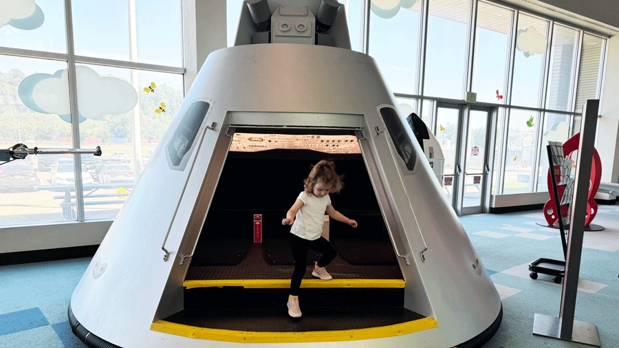 Toddler stepping out of a model spacecraft in the Kids Flight Zone at The Museum of Flight in Seattle
