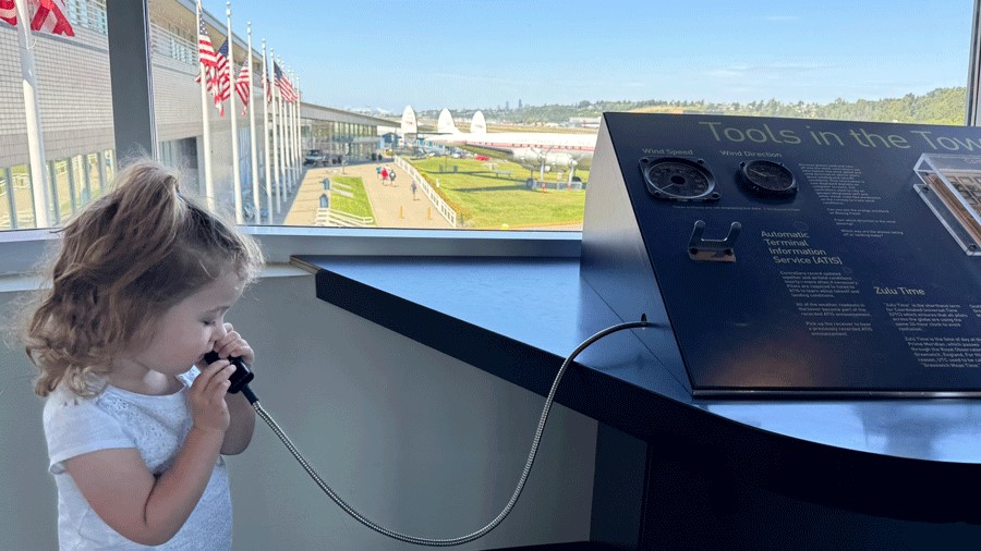 Toddler listening to recordings of air traffic controllers in the tower at The Museum of Flight in Seattle