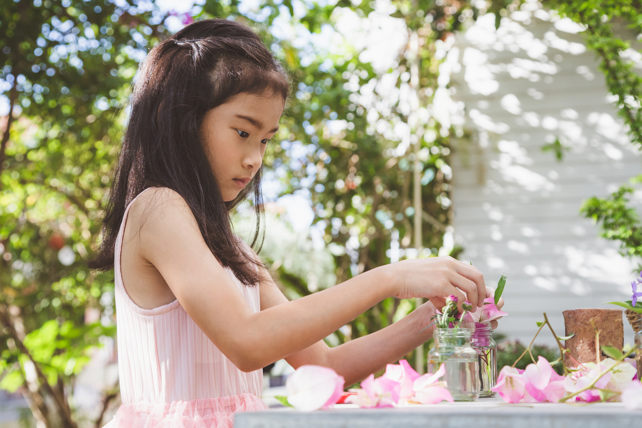 little girl playing with pink flowers