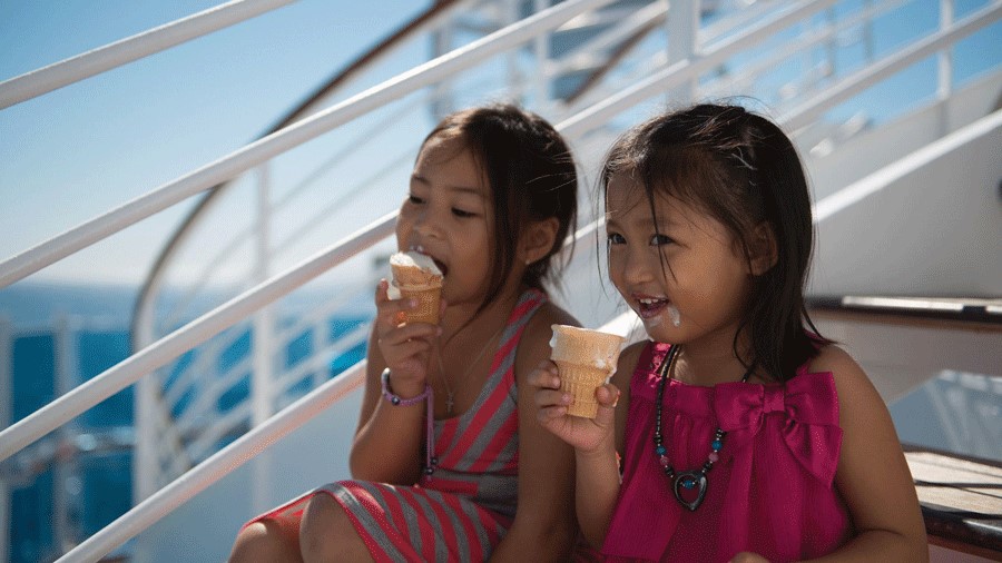 Two kids sitting on Alaskan cruise ship steps eating soft serve ice cream