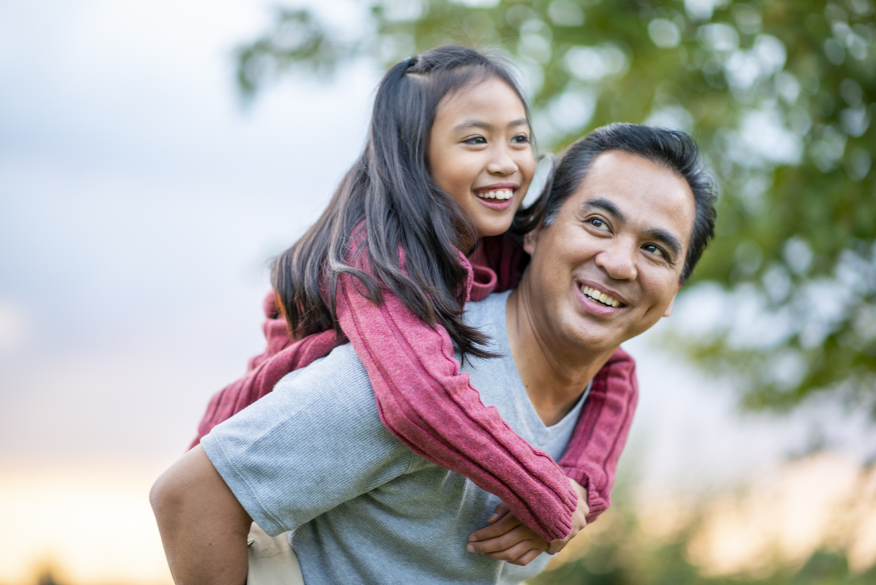 father giving his daughter a piggyback ride