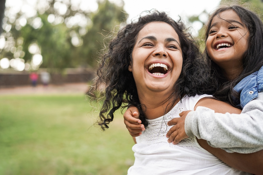 Mom with daughter on her back looking at her and both laughing