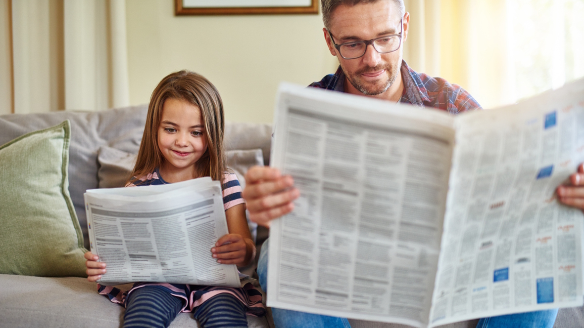 Dad and daughter reading the newspaper together