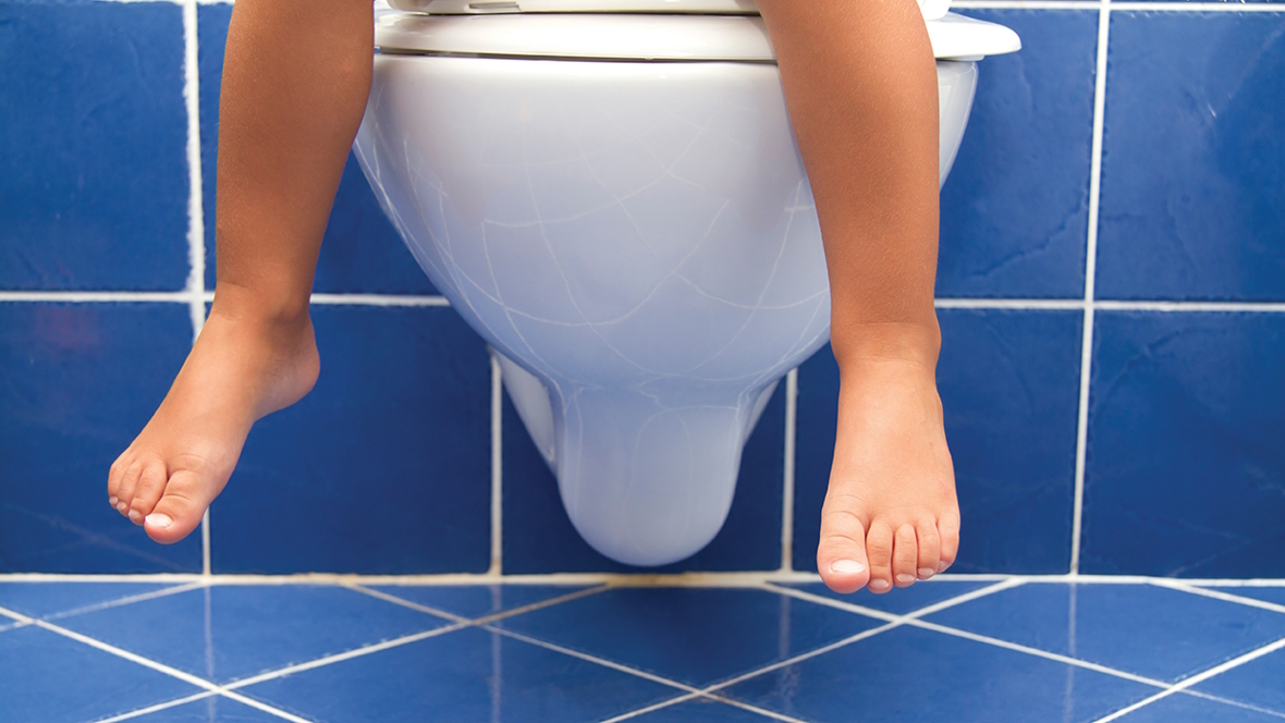 Child feet over the edge of a toilet potty training regression