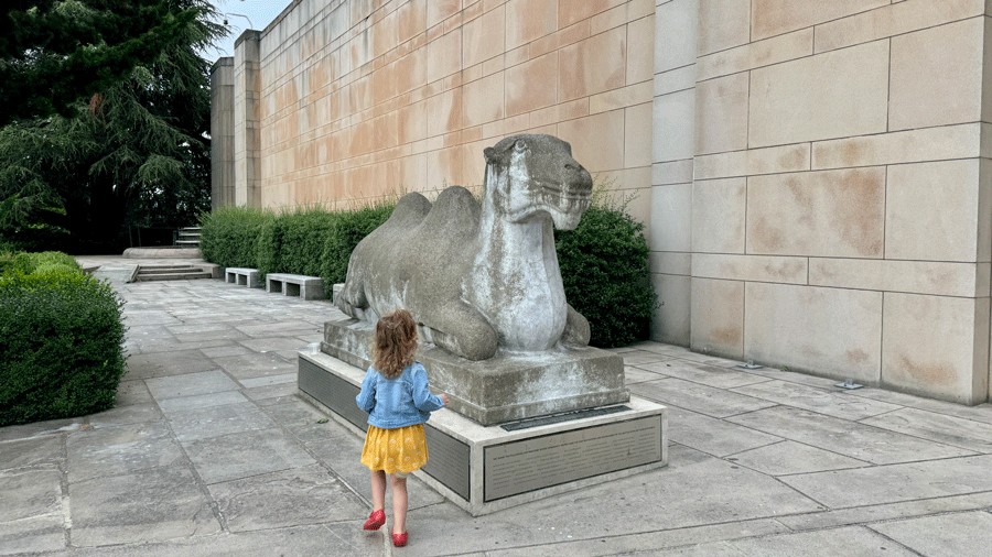 young girl looking at camel statue outside Seattle Asian Art Museum